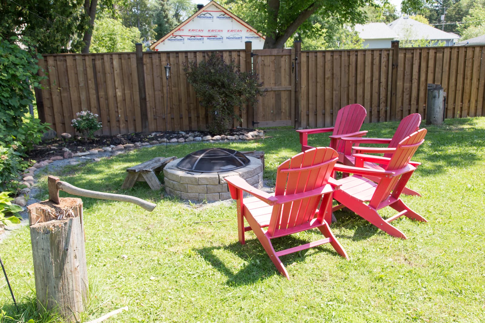 Adirondack chairs gathered around the stone fire pit on the back lawn, ready for an evening after the beach